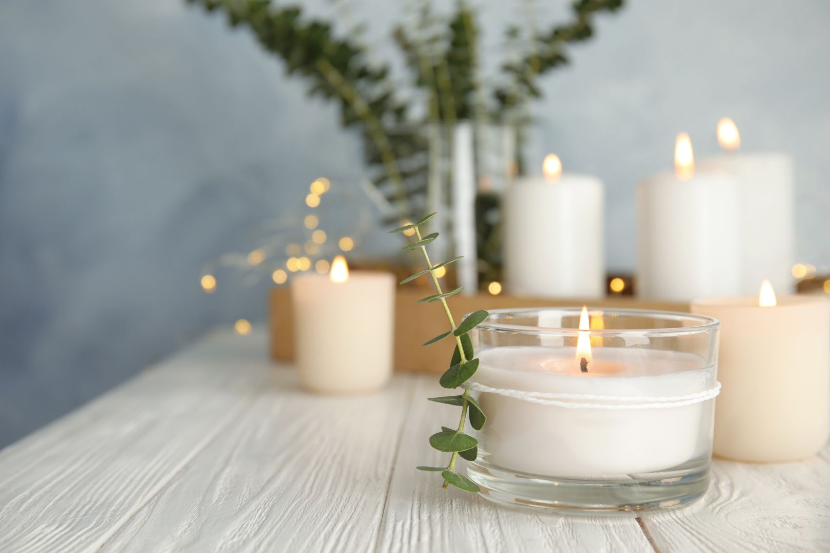 Burning Aromatic Candle And Eucalyptus Branch On Table.