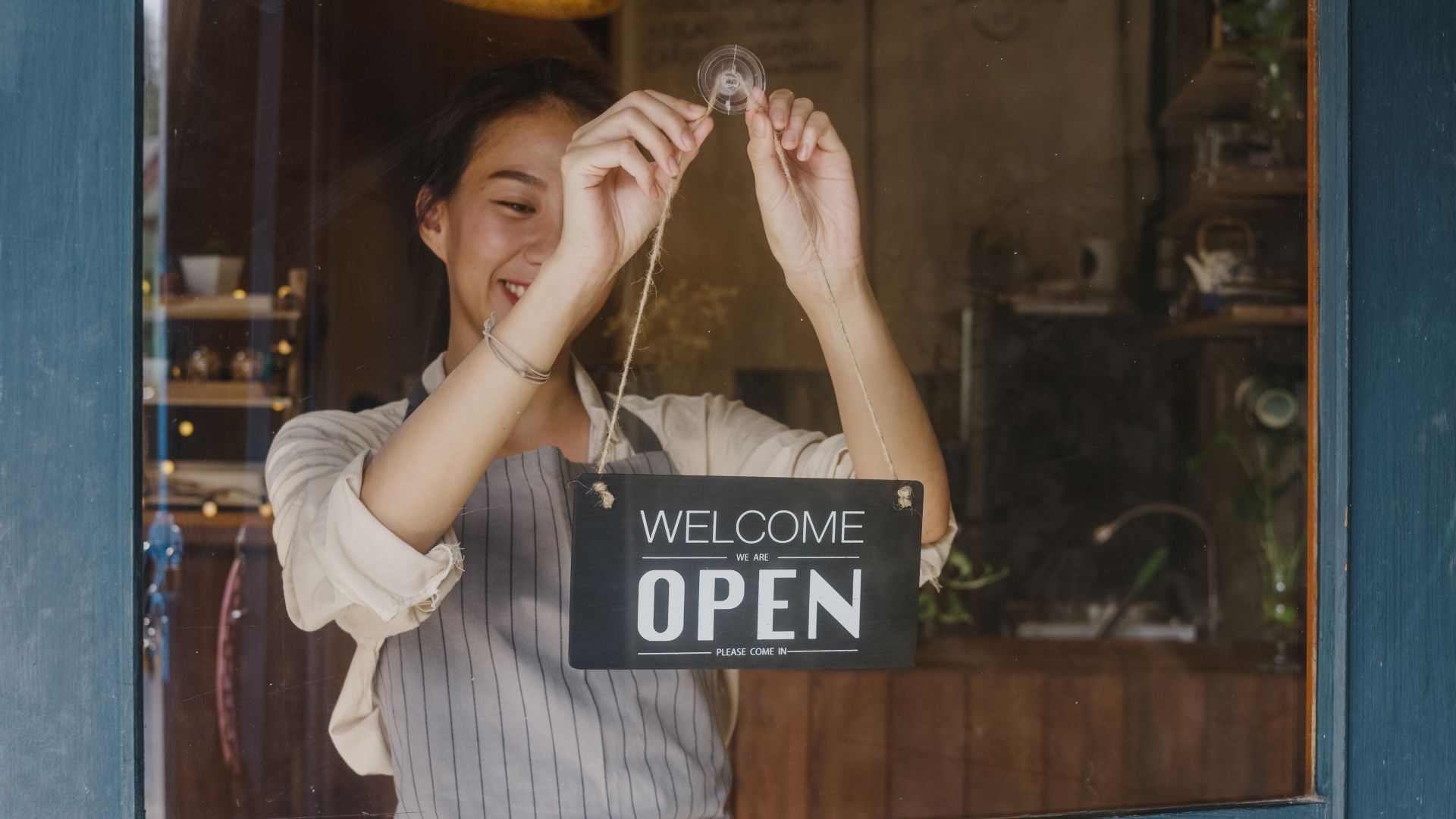 A young female manager changes a sign from a closed symbol to an open one